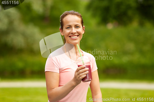 Image of woman drinking smoothie after exercising in park