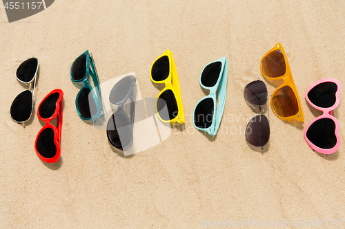 Image of different sunglasses on beach sand