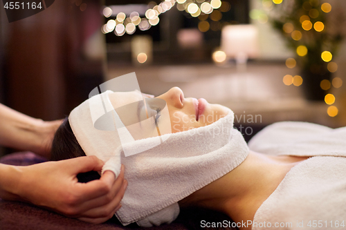 Image of woman having face massage with towel at spa