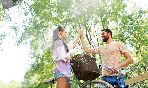 Image of couple with bicycles making high five in summer