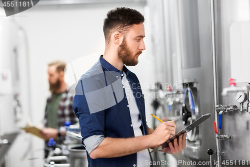 Image of man with clipboard at craft brewery or beer plant