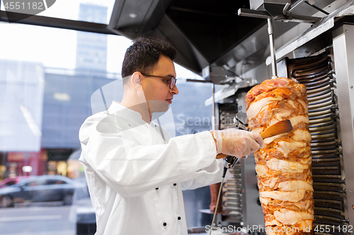 Image of chef slicing doner meat from spit at kebab shop