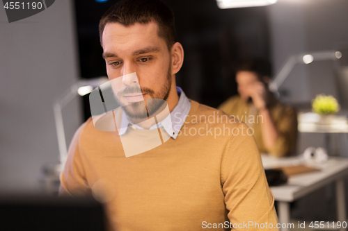 Image of man with computer working late at night office