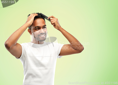 Image of happy indian man brushing hair with comb