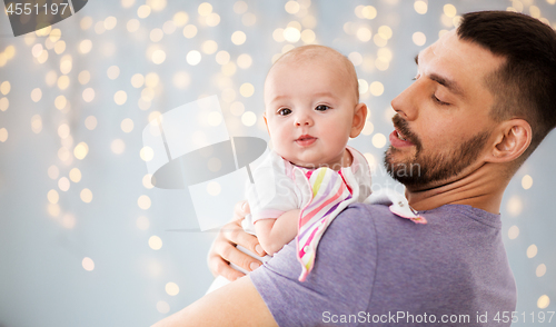 Image of father with little baby daughter over lights