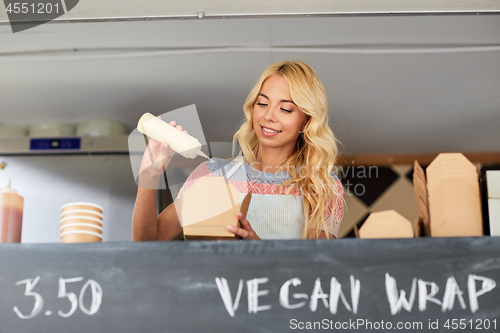 Image of happy saleswoman making wok at food truck