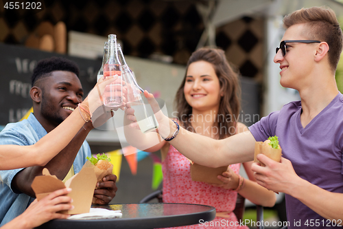 Image of friends clinking drinks and eating at food truck