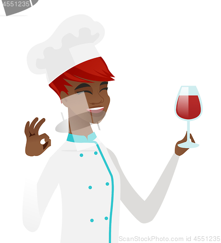 Image of Chef holding glass of wine and showing ok sign.