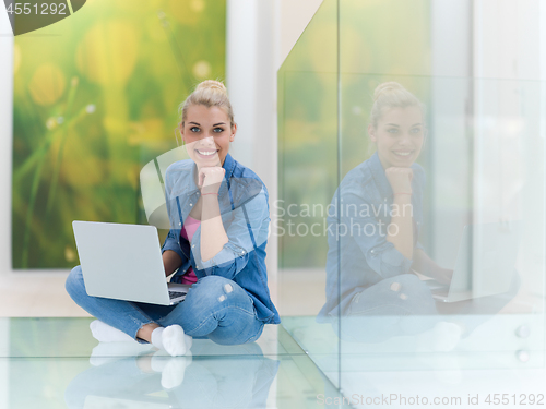 Image of young woman using laptop computer on the floor