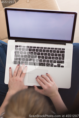 Image of young woman on sofa at home websurfing