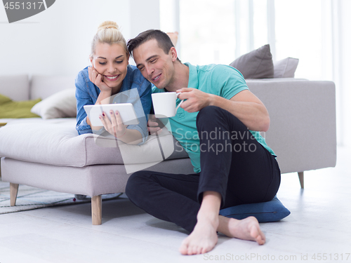 Image of couple relaxing at  home with tablet computers