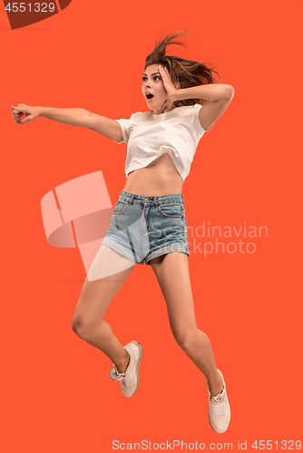 Image of Freedom in moving. Pretty young woman jumping against orange background