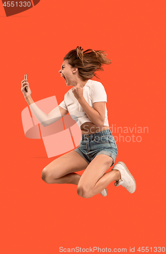 Image of Full length of pretty young woman with mobile phone while jumping