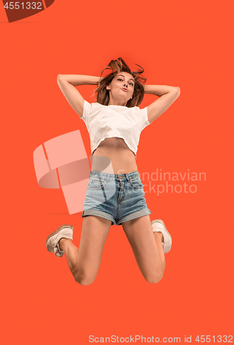 Image of Freedom in moving. Pretty young woman jumping against orange background