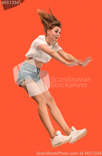 Image of Freedom in moving. Pretty young woman jumping against orange background