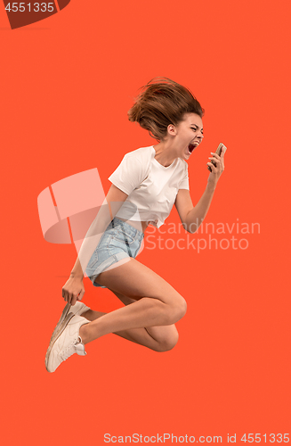 Image of Full length of pretty young woman with mobile phone while jumping