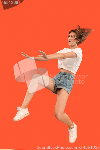 Image of Freedom in moving. Pretty young woman jumping against orange background