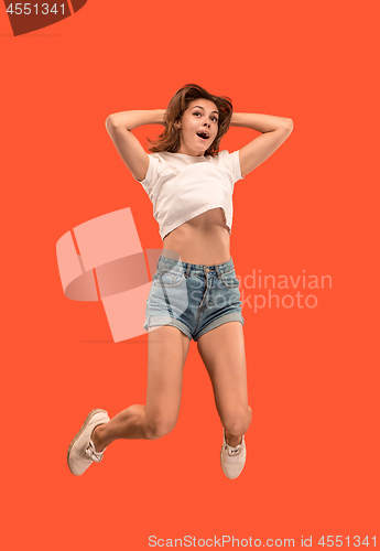 Image of Freedom in moving. Pretty young woman jumping against orange background