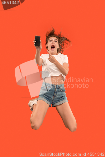 Image of Full length of pretty young woman with mobile phone while jumping