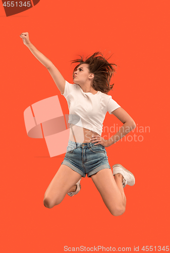 Image of Freedom in moving. Pretty young woman jumping against orange background