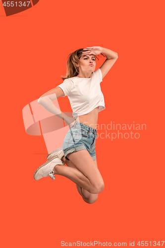 Image of Freedom in moving. Pretty young woman jumping against orange background