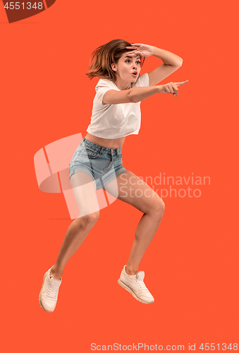 Image of Freedom in moving. Pretty young woman jumping against orange background