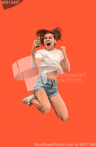 Image of Full length of pretty young woman with mobile phone while jumping