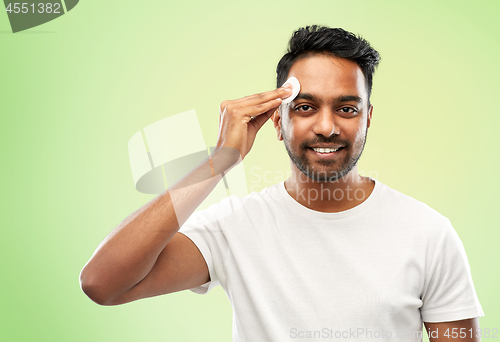 Image of smiling indian man cleaning face with cotton pad
