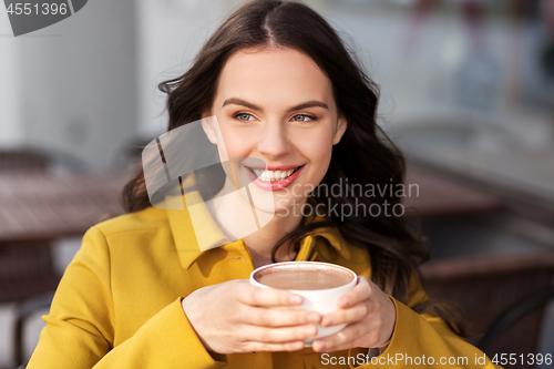 Image of teenage girl drinking hot chocolate at city cafe