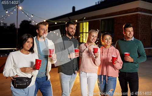 Image of friends with party cups on rooftop at night