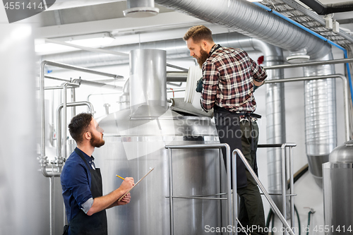 Image of men with clipboard at brewery kettle or beer plant