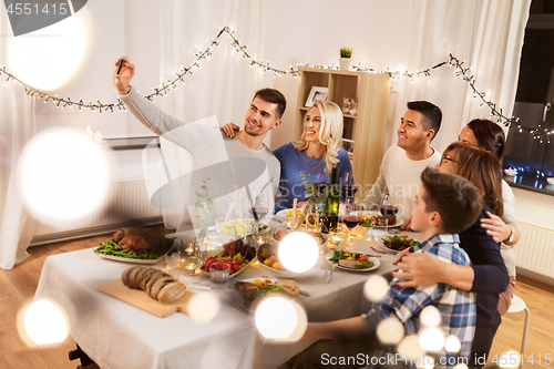 Image of family having dinner party and taking selfie