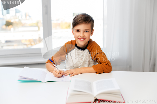 Image of boy doing homework and writing to notebook at home