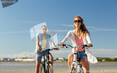 Image of happy young couple riding bicycles at seaside