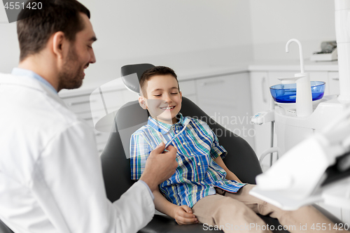 Image of dentist giving toothbrush to kid patient at clinic