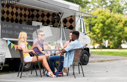 Image of friends with drinks sitting at table at food truck