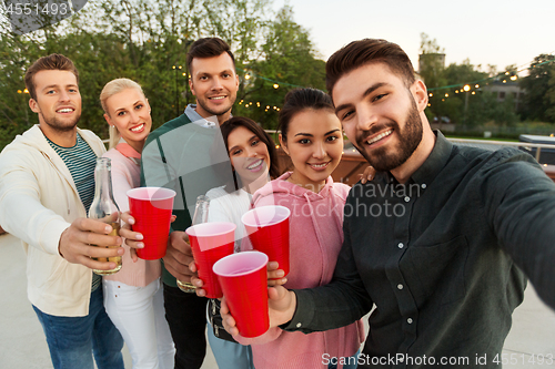 Image of friends with drinks taking selfie at rooftop party