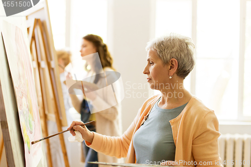 Image of senior woman painting at art school studio