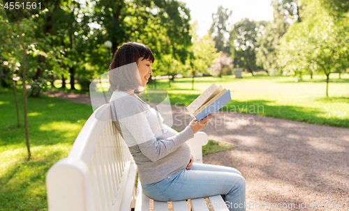 Image of happy pregnant asian woman reading book at park