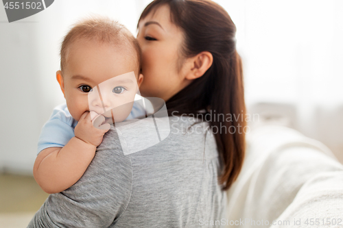 Image of close up of happy mother kissing baby son at home