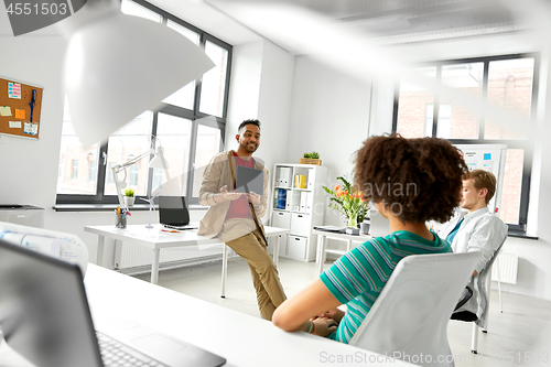 Image of man showing tablet pc to creative team at office