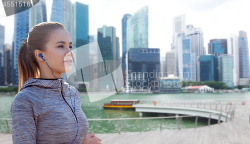 Image of happy woman with earphones over singapore city