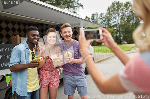 Image of woman photographing friends eating at food truck