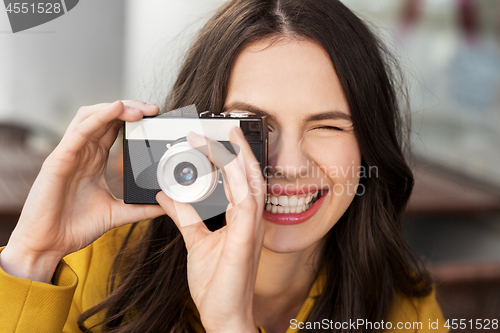 Image of happy young woman with film camera outdoors