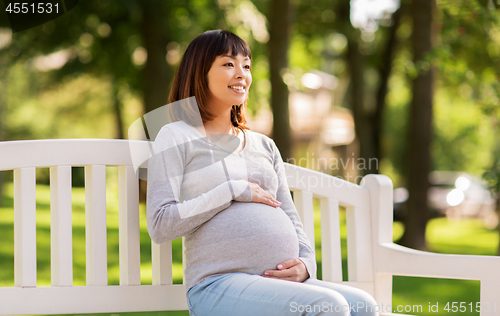 Image of happy pregnant asian woman sitting on park bench