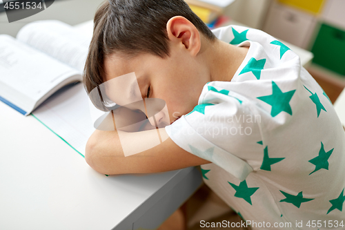 Image of tired student boy sleeping on table at home