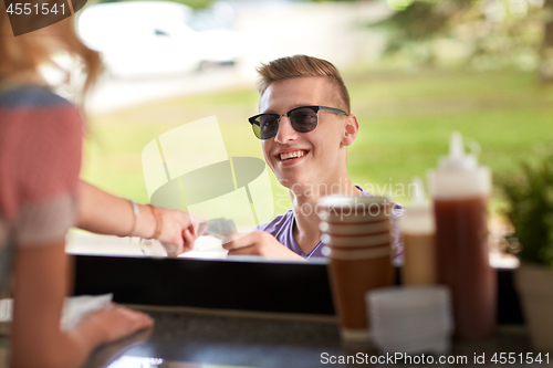 Image of happy young man paying money at food truck