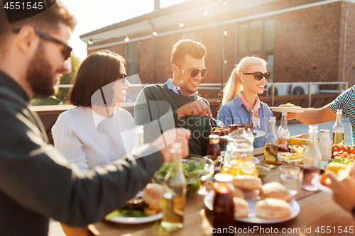 Image of happy friends eating at barbecue party on rooftop