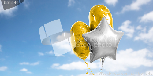 Image of three gold and silver helium balloons on white