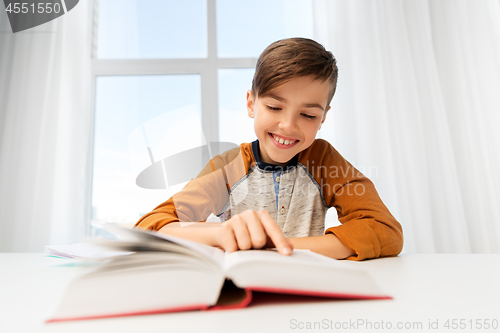 Image of student boy reading book at home table